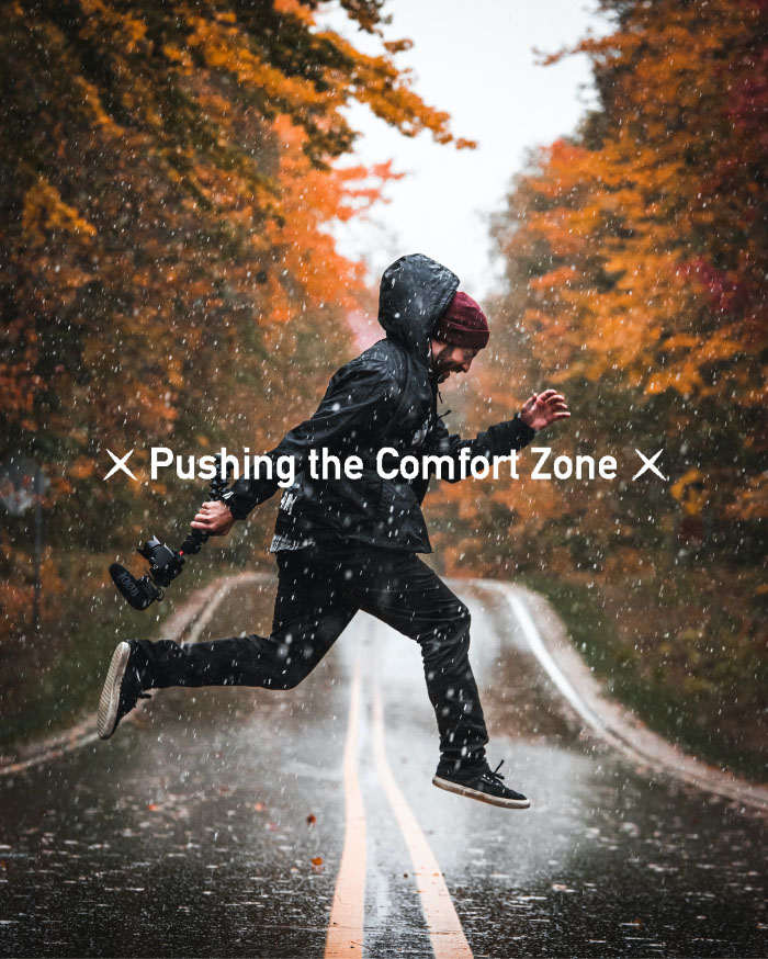Man wearing rainjacket jumping over road in rainy weather